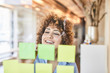 Happy businesswoman brainstorming with post-its on glass pane