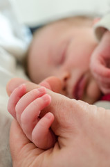 hand of newborn baby holding male adults finger. concept of help and family. father holding hand.