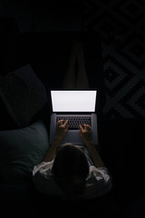 young woman with laptop on the sofa at night