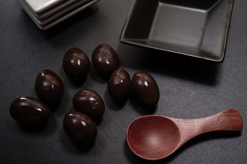 Chocolate round with cocoa powder wooden spoon and plate on top of Black rock stone plate