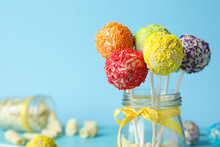 Yummy Bright Cake Pops In Glass Jar With Bow On Color Background. Space For Text