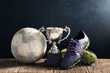 Fototapeta Sport - still life photography : old football, football shoes and trophy on old wood table in championship concept