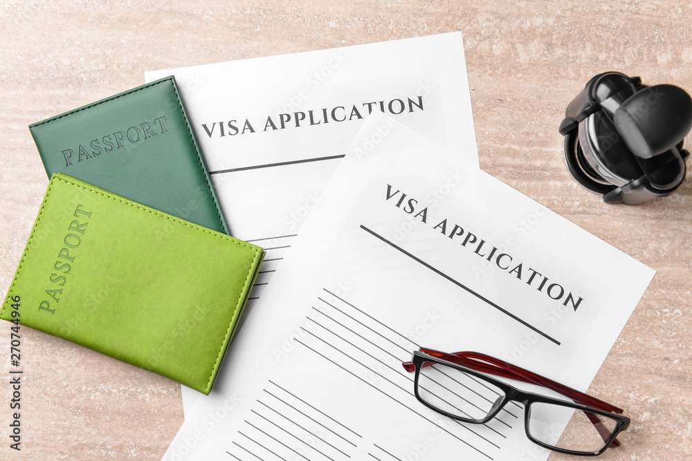 Visa application forms, passports, stamp and glasses on table. Concept of immigration