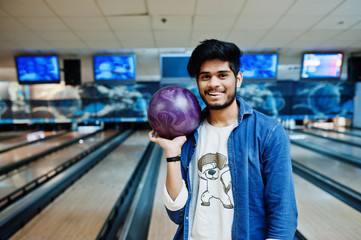 Stylish beard asian man in jeans shirt standing at bowling alley with ball at hand.