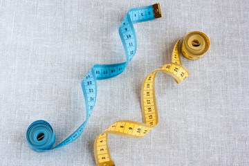 two centimeter measuring tape yellow and blue on a light gray background close-up selective focus