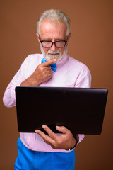 Senior handsome man wearing stylish clothes against brown backgr