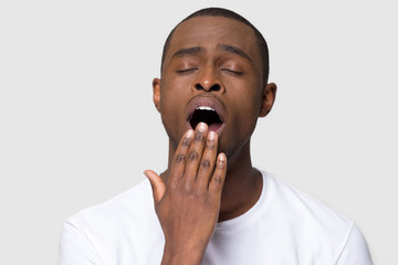 Tired african man yawning cover mouth with hand studio shot