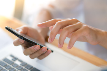 Business woman hand with Financial charts and mobile phone over laptop on the table .