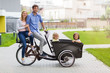 © pikselstock - Young family having a ride with cargo bike