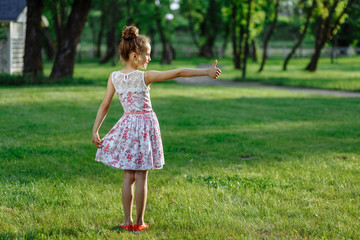 Cute little girl on the meadow in rose dress on sunset. Posing like ballerine. Childhood concept.