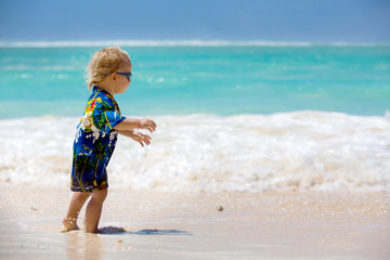 Wall Mural - Happy beautiful fashion family, mom and children, dressed in hawaiian shirts, playing together on the beach