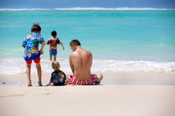 Poster - Happy beautiful fashion family, mom and children, dressed in hawaiian shirts, playing together on the beach