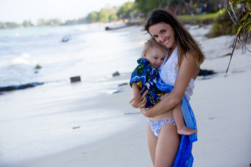 Sticker - Mom and toddler boy, happily hugging on the ocean shore, relaxing