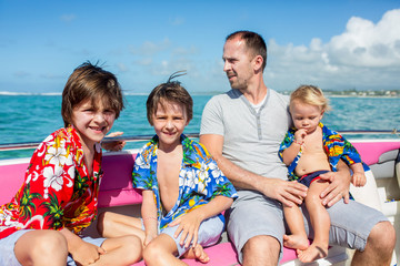 Canvas Print - Happy beautiful fashion family, children and parents, dressed in hawaiian shirts, enjoying day trip with speed boat