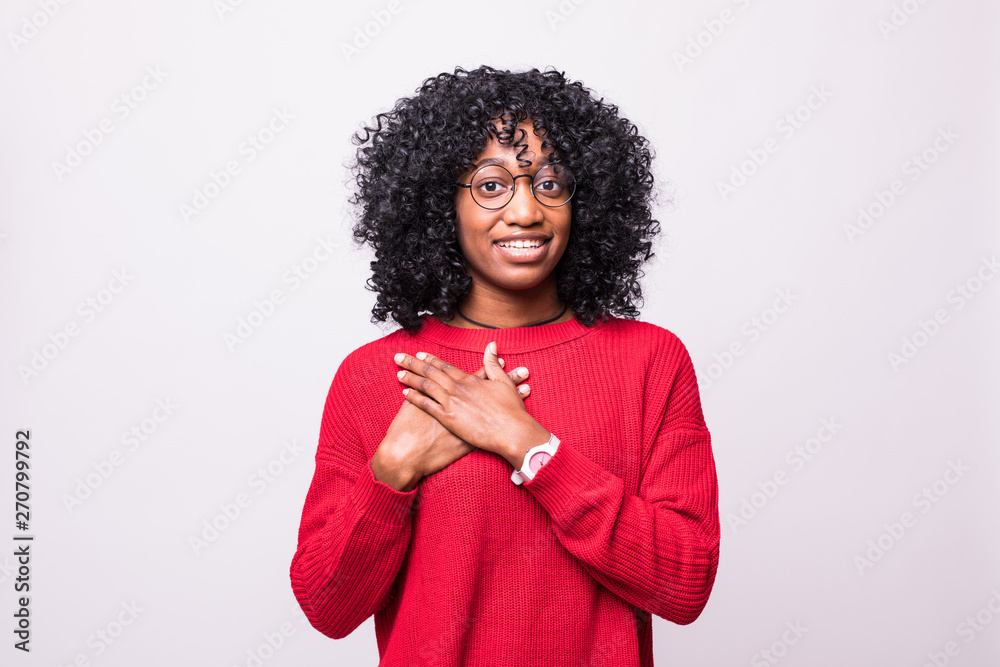 Friendly looking woman with Afro hairstyle, keeps hands on chest, feels ...