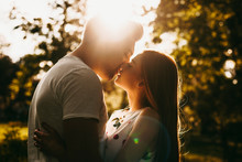 Side View Portrait Of A Amazing Couple Kissing Against Sunset Outside While Traveling In Their Vacation Time.