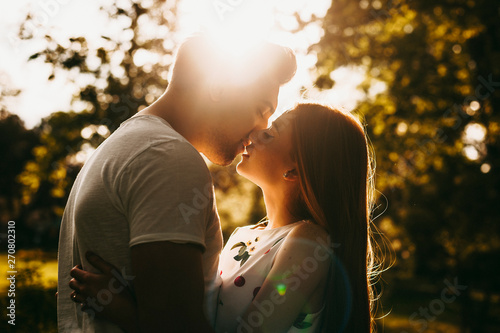 Fotografía Side view portrait of a amazing couple kissing against sunset outside while traveling in their vacation time