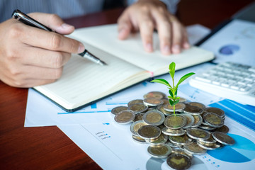 Businessman accountant making notes at report doing finances and calculate about cost of investment and analyzing financial data, growing business to profit and saving with wealth management