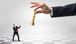 © ra2 studio - Small businessman fighting against big chessman on a big hand with chess board concept