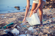 © Aleksej - Woman collect garbage on the beach. Environmental pollution concept