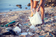 Woman collect garbage on the beach. Environmental pollution concept