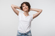 © Drobot Dean - Image of optimistic woman in basic t-shirt touching her hair and looking aside