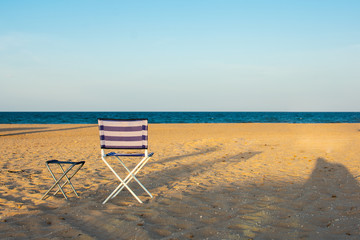 A beach chair on an empty beach at sunset