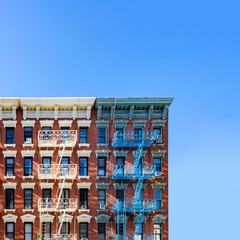 Fototapete - Old New York City apartment building exterior with fire escapes and windows and empty blue sky above in the Alphabet City Neighborhood of Manhattan