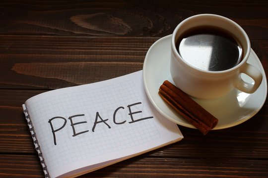 Peace inscription and word in a notebook near a cup of coffee