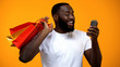 © motortion - Excited black male holding shopping bag and smartphone, cash back services