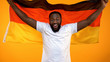 © motortion - Smiling black man with German flag cheering for national sport team victory