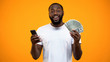 © motortion - Excited Afro-American man holding smartphone and dollars, online money transfer