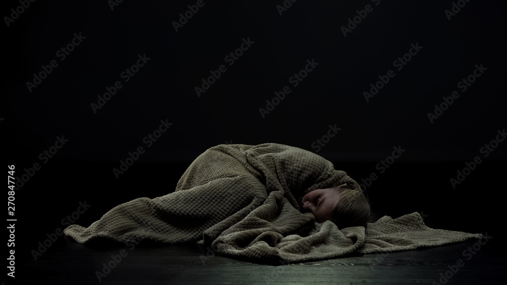 Girl covered in plaid lying on floor of dark room, domestic violence victim - obrazy, fototapety, plakaty 
