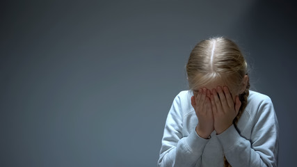 Wall Mural - Unhappy little kid closing eyes with hands, bullying and family violence victim