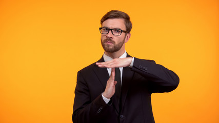 Business person showing time-out gesture, isolated on orange background deadline