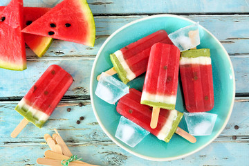 Wall Mural - Homemade watermelon popsicles on a plate. Top view on a rustic blue wood background. Summer food concept.