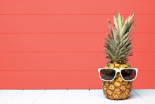 Hipster Pineapple With Sunglasses Against A Living Coral Colored Wood Background. Minimal Summer Concept.