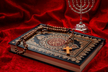 Religious coexistence, monotheism and abrahamic religions coexist in peace concept theme with a quran representing islam, a cross and rosary symbolizing christianity and menorah a symbol of judaism