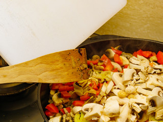 Adding mushrooms to pan vegetables.