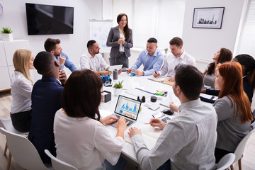 Smiling Young Businesswoman Giving Presentation In The Meeting