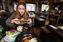 Woman Using Smartphone Taking A Photo Of Food In Restaurant