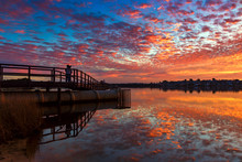 Mirror Image Reflection Of Pier And Couple At Sunset At River In Australia