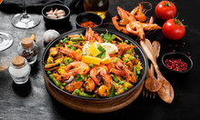 Traditional Spanish Seafood Paella In The Fry Pan On A Black Wooden  Table.