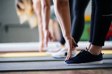 Flexibility, activity, yoga, pilates, warming up concept. Women hands stretching to toecaps on group workout