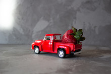 Red Strawberry On Old Vintage Red Toy Truck Car. Fruits And Transportation Concept In Macro. Close-up Food Logistics Visualisation.