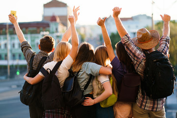 Traveling, sightseeing, group travel, city tour, student exchange program, vacation, holiday, togetherness and friendship. People with backpacks rising hands, joy and positivity