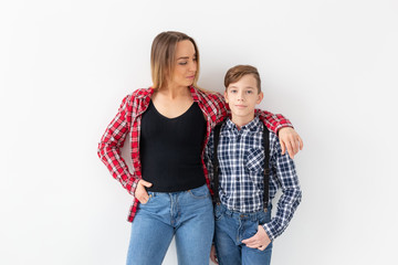 Wall Mural - Family, fashion and mothers day concept - Portrait of mother and son dressed in plaid shirts on white background