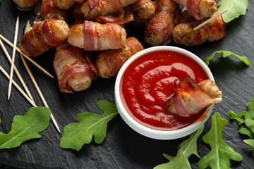 Wall Mural - Party finger food pigs in blankets on toothpicks with ketchup sauce and wild rocket leaves