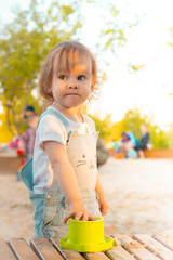 Little smiling girl playing with sand in sandbox in summer