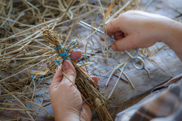 Wall Mural - Straw toy in the form of a cross in the hands of an elderly woman